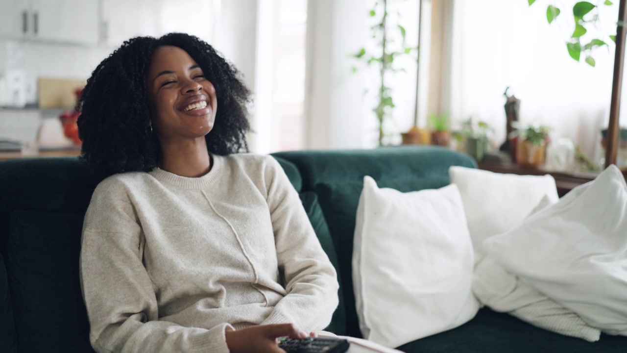 Happy African American Woman Watching TV and Laughing on Couch