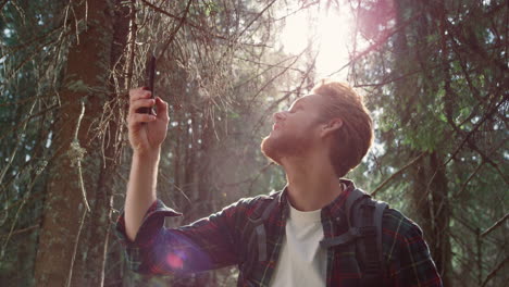 männlicher wanderer, der versucht, ein mobilfunknetz im wald zu finden