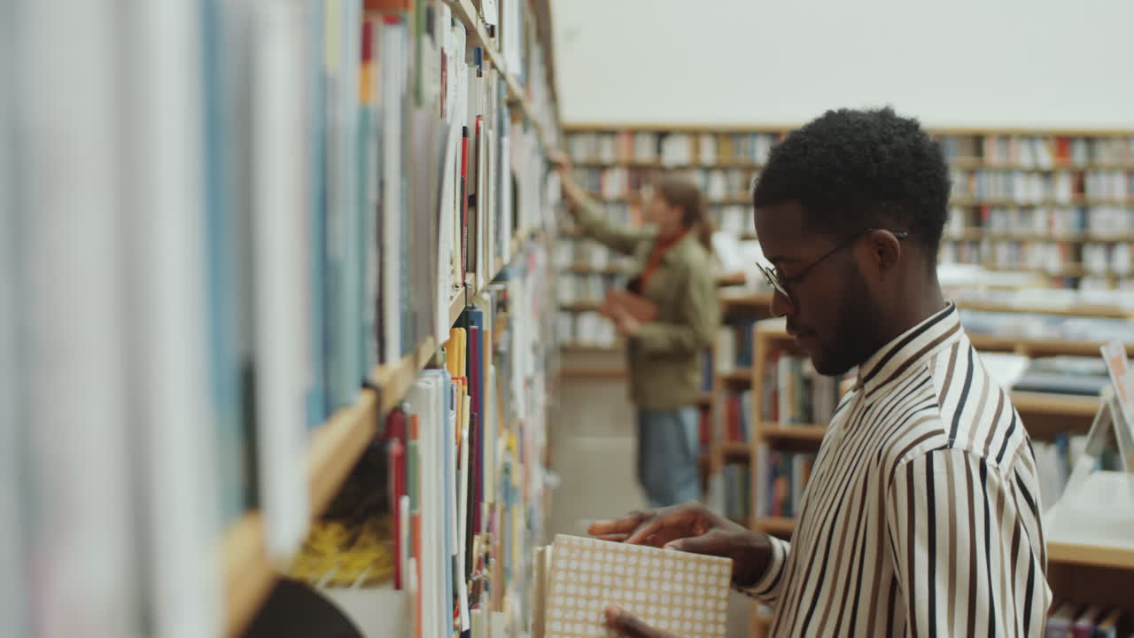 hombre negro eligiendo un libro en la biblioteca