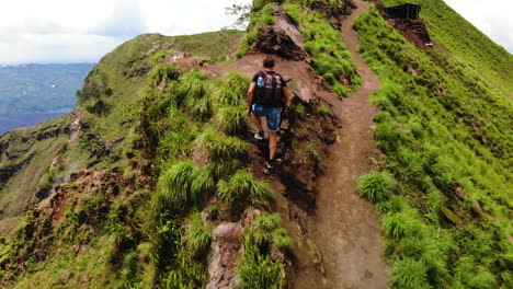 drone siguiendo a un turista europeo que lleva una mochila, caminando hasta la cima de un volcán activo monte batur en bali, indonesia