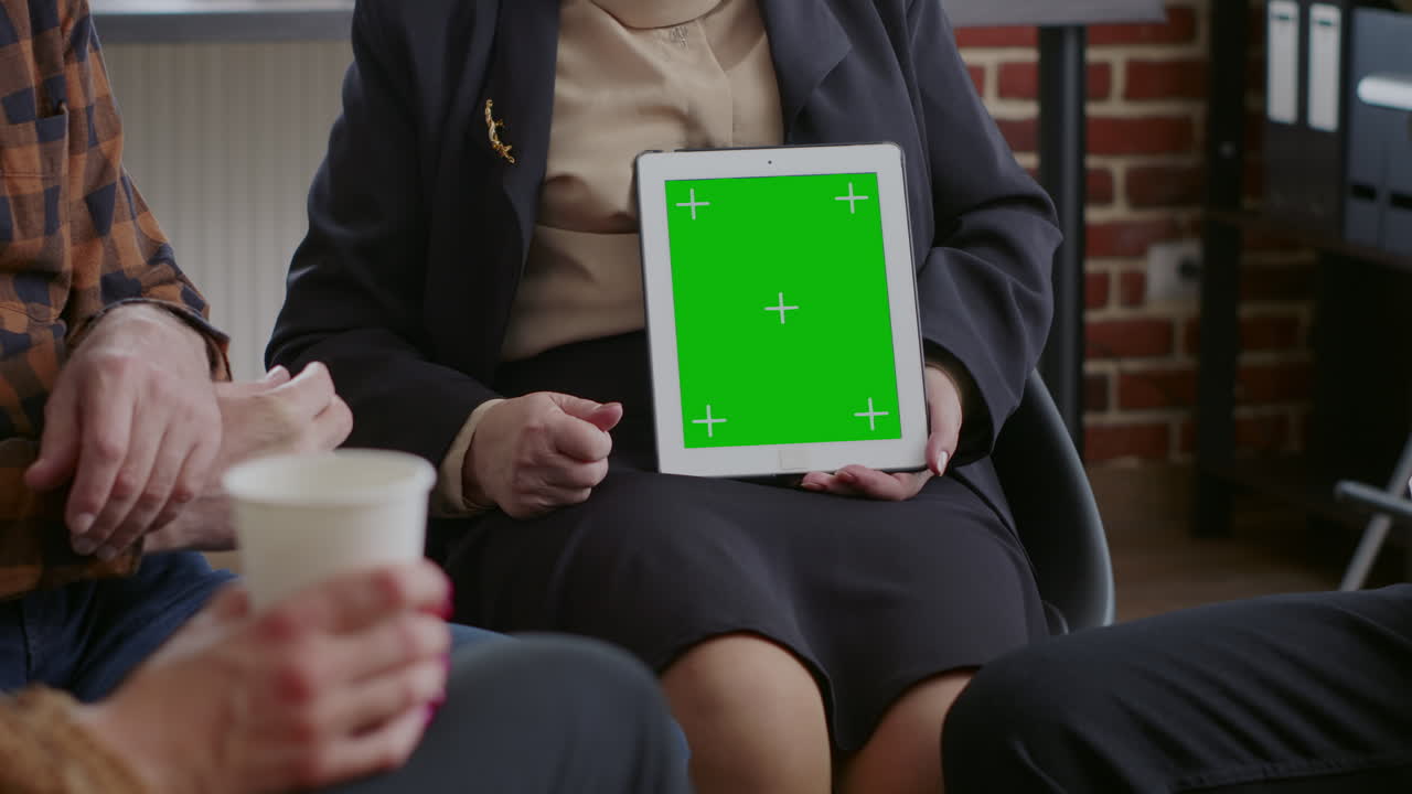 Close up of counselor vertically holding green screen on tablet at aa therapy session