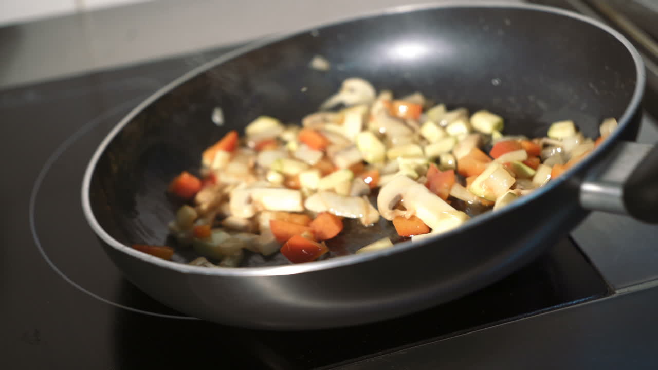 Stewed sliced vegetables in pan. Fried mushrooms with vegetables in frying pan