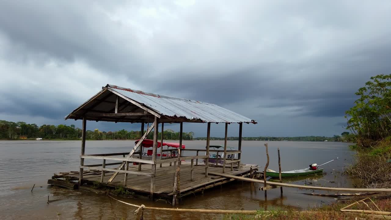 A rustic dock on the river in the Amazon rainforest, showcasing calm waters and a small boat