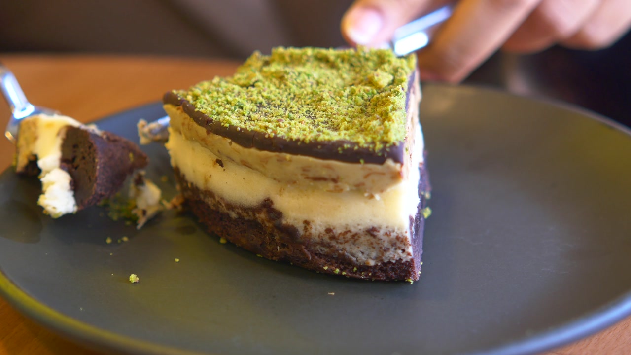 Close-up of a Person Cutting a Slice of Pistachio Chocolate Cake