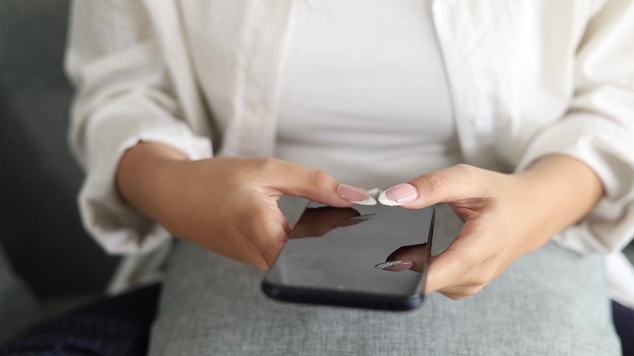 Le mani di una giovane donna che tengono un telefono. Chatta, tocca, scorre. Primo piano