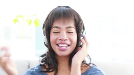 Mujer-Con-Auriculares-Escuchando-Música-En-El-Sofá.