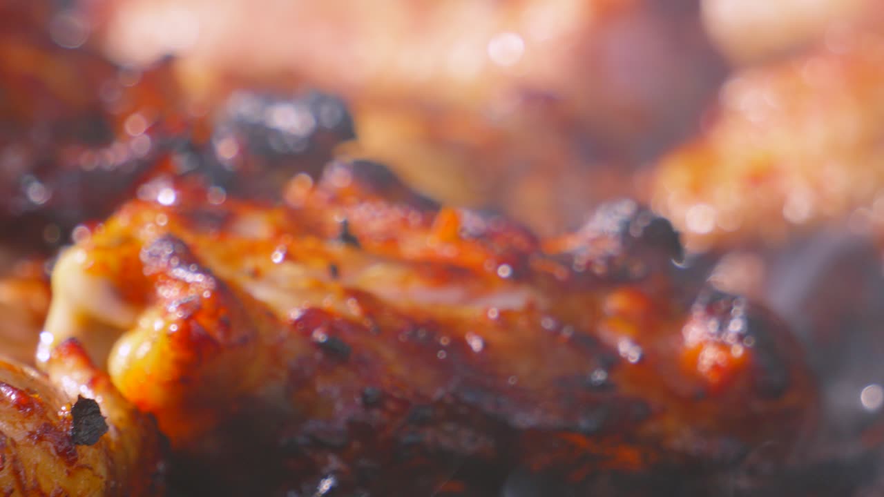 Marinated Chicken Thigh Close Up with Smoke Covering Pieces of Meat as Chef Places Drumstick onto Flame BBQ Grill with Tongs. Seasoned Tasty Summer Outdoor Food.