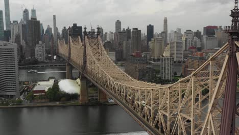 Lange,-Seitlich-Verschiebbare-Drohnen-Luftaufnahme-Der-Queensboro-Brücke-Mit-Blick-Auf-Manhattan,-New-York-Und-Queens-Bei-Tag-Mit-Autos,-Die-Manhattan-Auf-Der-Brücke-Verlassen,-Und-Booten