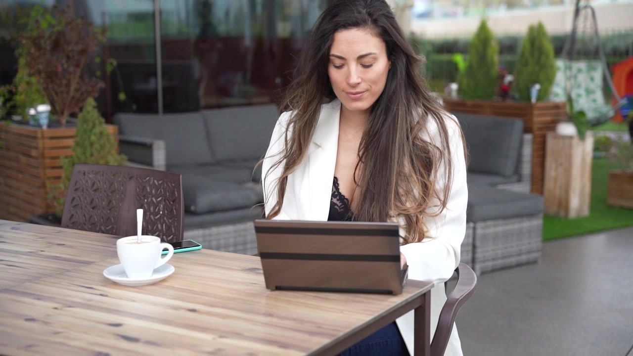 Mujer joven trabajando en su portátil en una cafetería moderna.