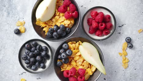 golden cornflakes with fresh fruits of raspberries  blueberries and pear in ceramic bowl