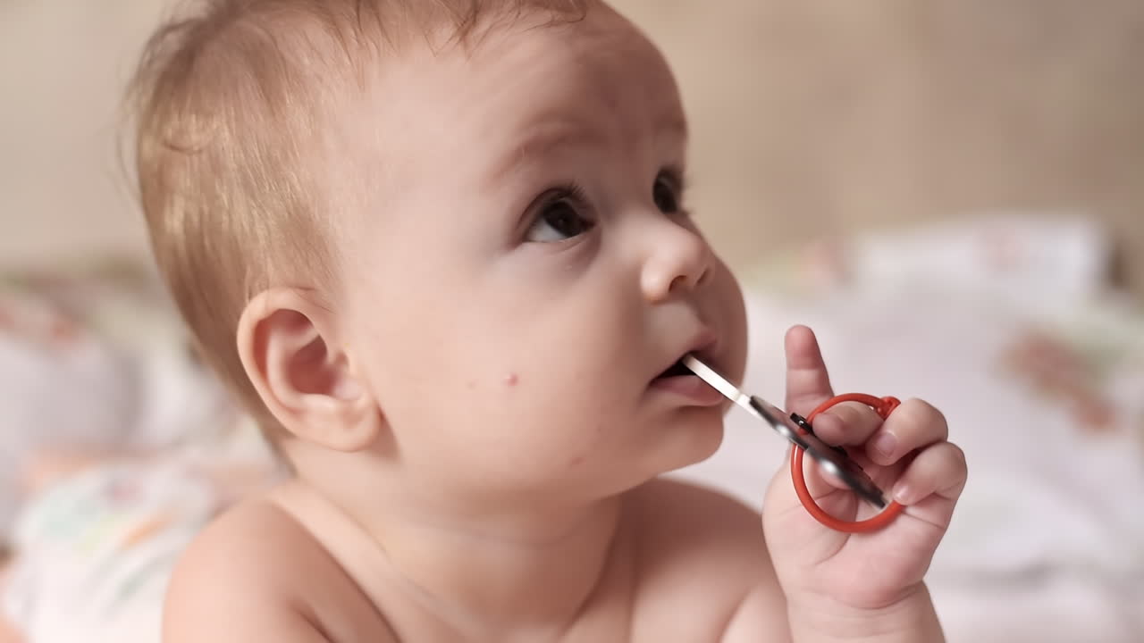 Caucasian blonde baby boy on a bed, playing with toy
