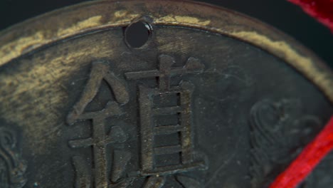 dreamy macro shot of a chinese ancient traditional lucky coin, asian new year decoration, golden shiny blur background, flare leak, red strings, culture holyday, smooth slow pan right 4k video