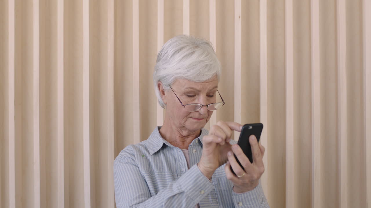 portrait of beautiful elderly retired woman texting browsing using smartphone senior female eyesight problem