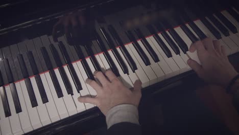 Male-pianist-performing-a-song-on-piano-with-low-light-and-over-the-shoulder-view