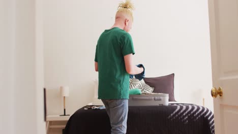 Albino-african-american-man-with-dreadlocks-packing-a-suitcase-for-vacation