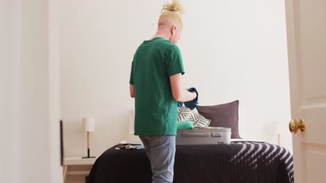 albino african american man with dreadlocks packing a suitcase for vacation