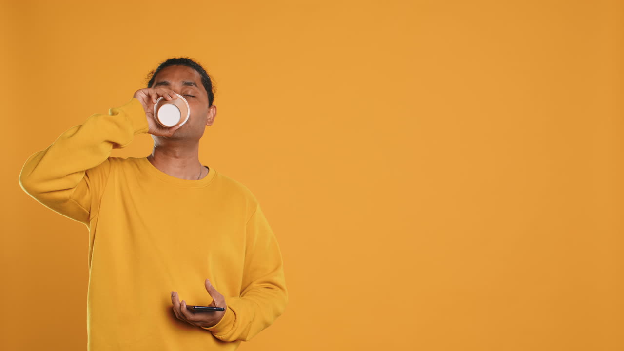 hombre bebiendo café y charlando con amigos en el teléfono móvil, fondo de estudio