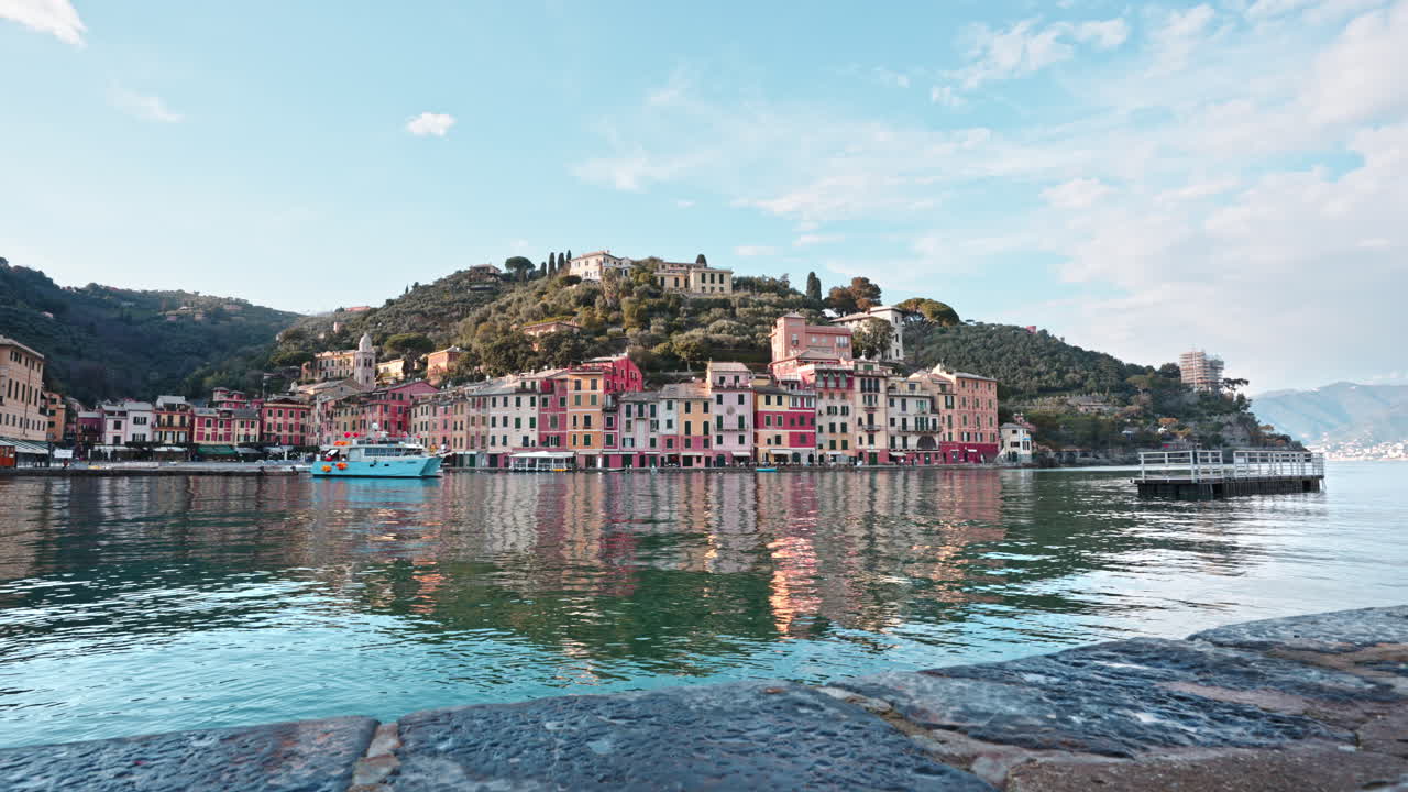 파란색 관광 페리 보트 가 다채로운 집 들 이 있는 작은 포르토피노 항구 에 정박 하고 있다