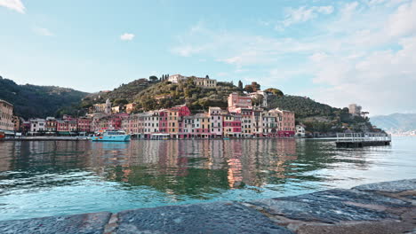 barco de ferry turístico azul atracado en el pequeño puerto de portofino con casas coloridas