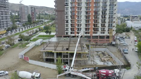 camiones mezcladores, grúas móviles y trabajadores manuales durante el vertido de hormigón de losa en el sitio de construcción