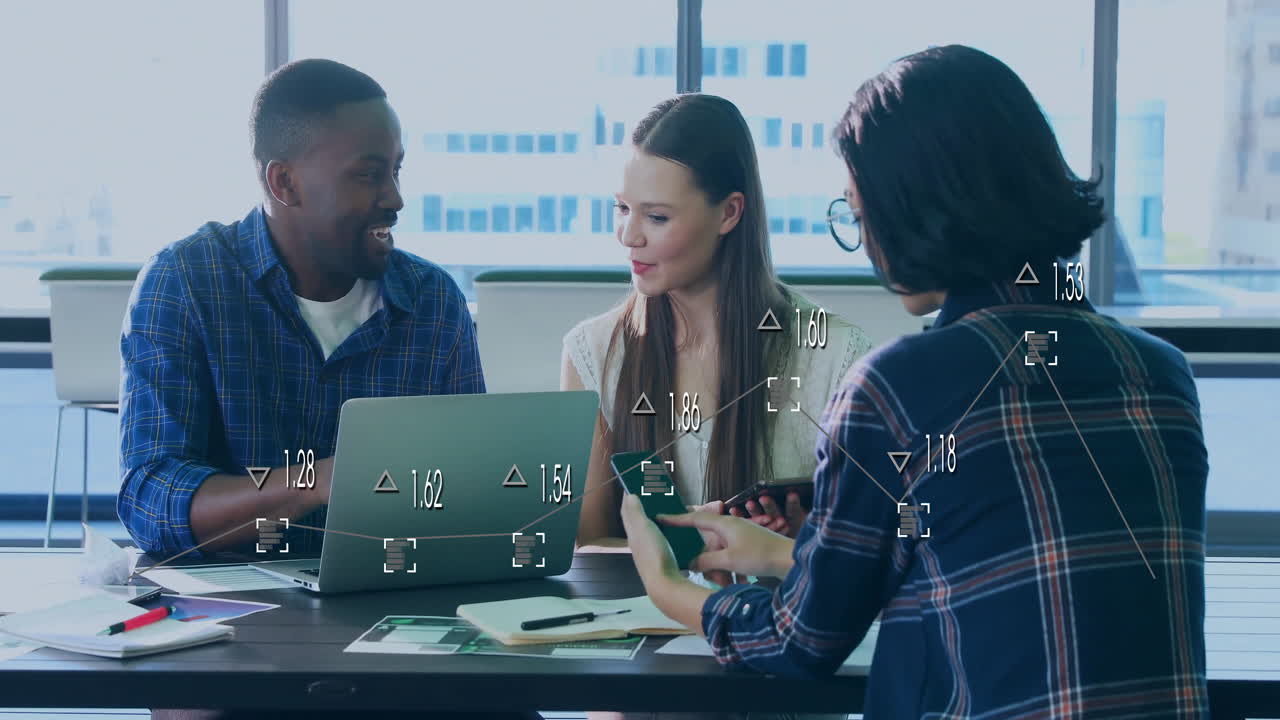 Colleagues reviewing business analytics in office, showing floating graphs on laptop and smartphone