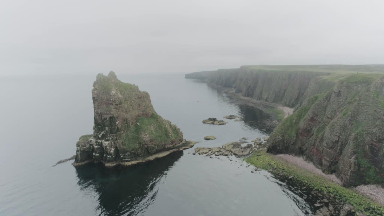 Pomalý statický záběr dronem na skalní útvary Stacks of Duncansby za mlhavého počasí podél trasy Scotland North Coast 500 u John O'Groats.