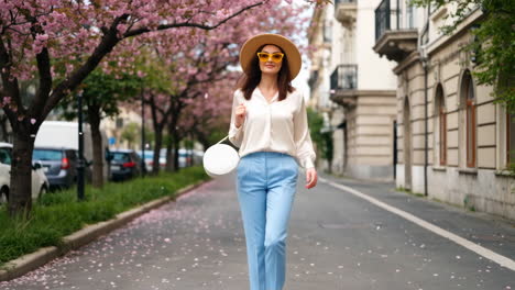a woman walking down a cherry blossom-lined street in spring