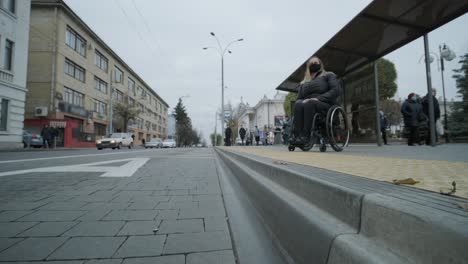 woman in a wheelchair waiting for a bus at a bus stop