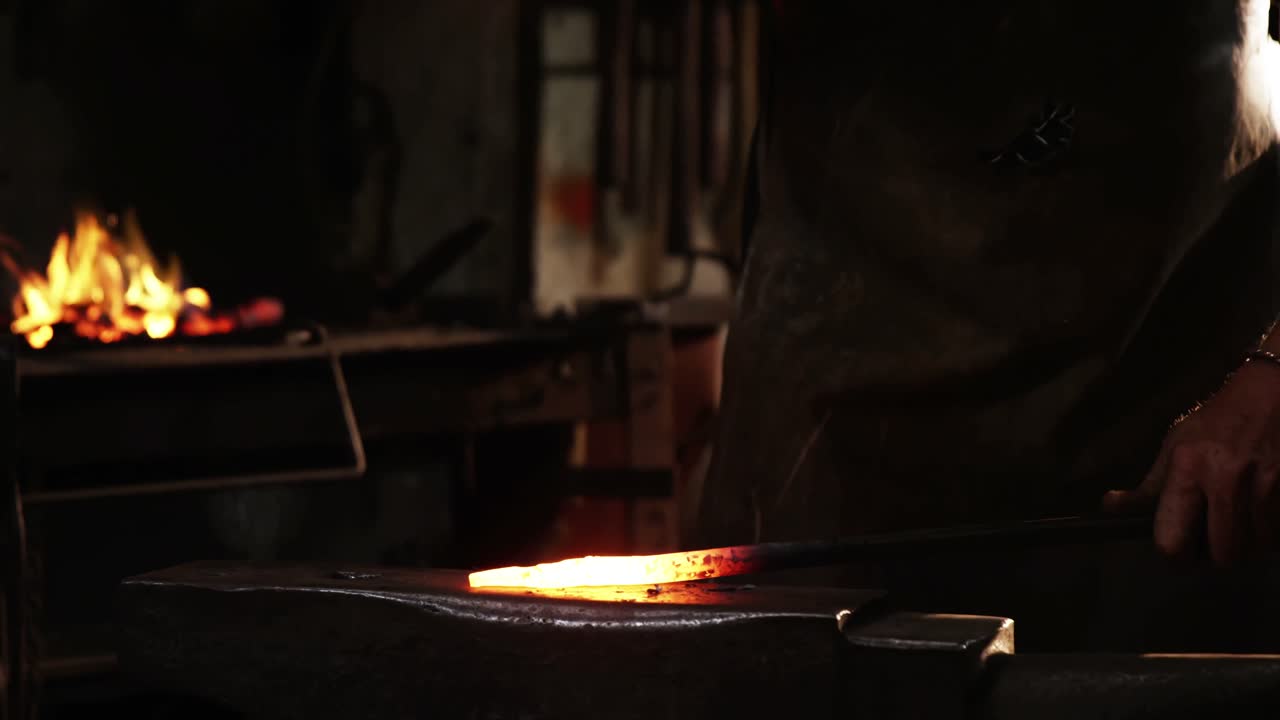 Mid-section of blacksmith working on a iron rod