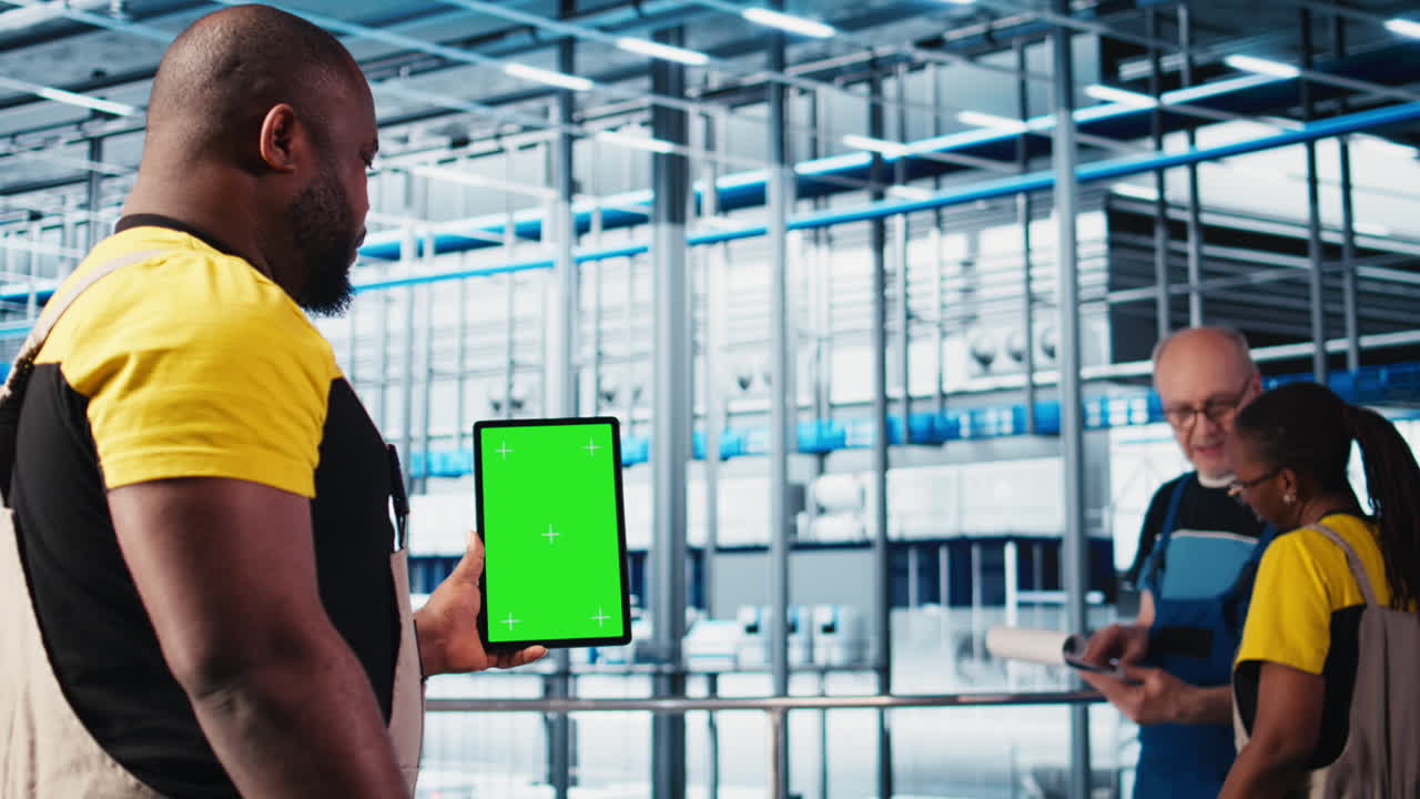 Smart factory expert using green screen tablet to test automated systems