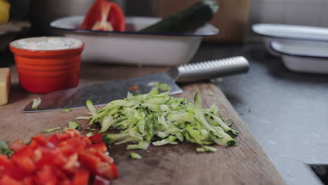 diced zucchini- courgette being dropped onto wooden chopping board