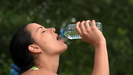 una bonita morena bebiendo de una botella de agua