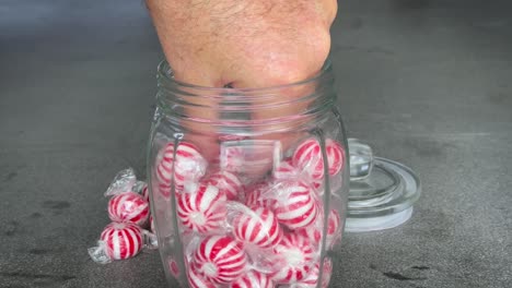 person taking hard candy from a glass jar