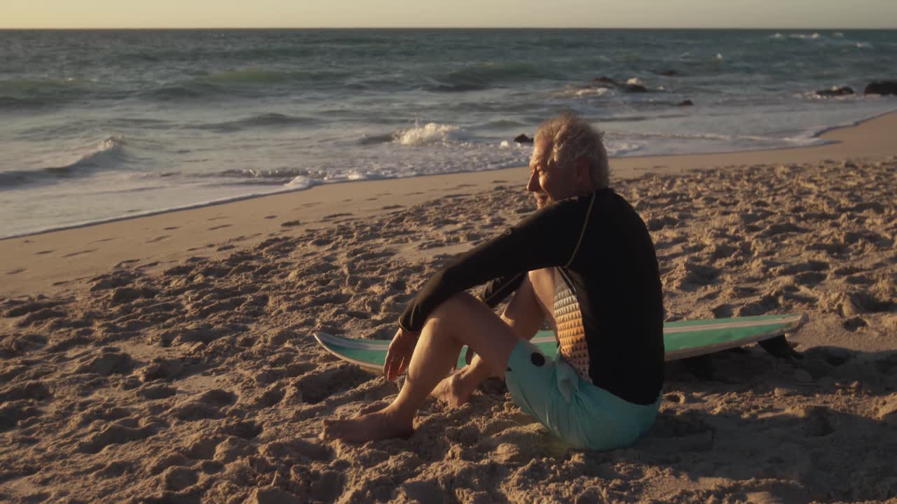 hombre mayor sentado en la arena en la playa