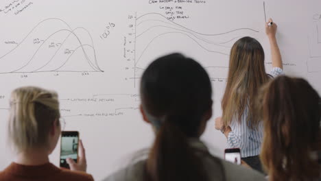 joven mujer de negocios hispana compartiendo ideas corporativas con colegas del grupo de gestión usando un teléfono inteligente filmando video disfrutando de la presentación compartiendo en las redes sociales en una reunión de seminario en la sala de juntas