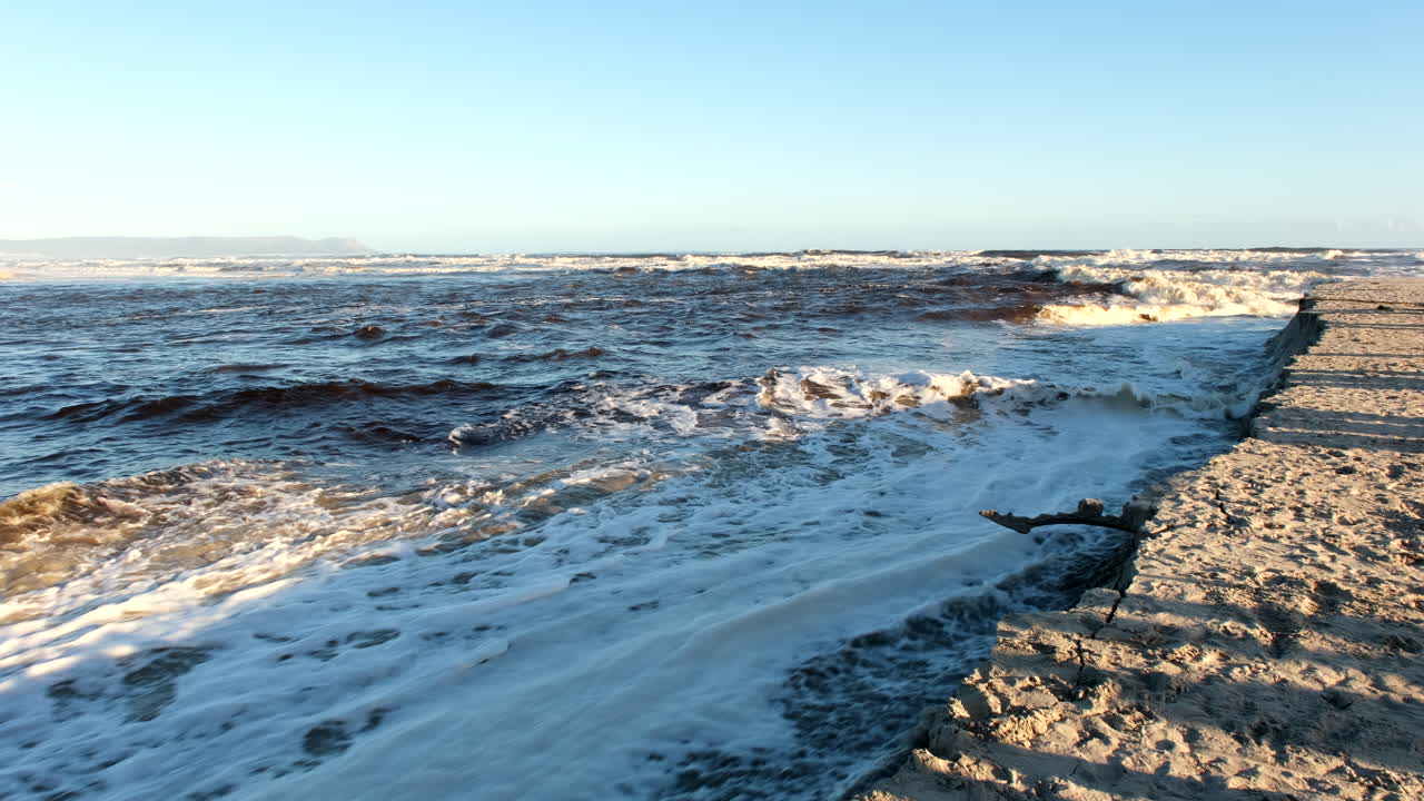 Riflusso di acqua di mare alla foce del fiume durante l'alta marea al tramonto, erosione della spiaggia