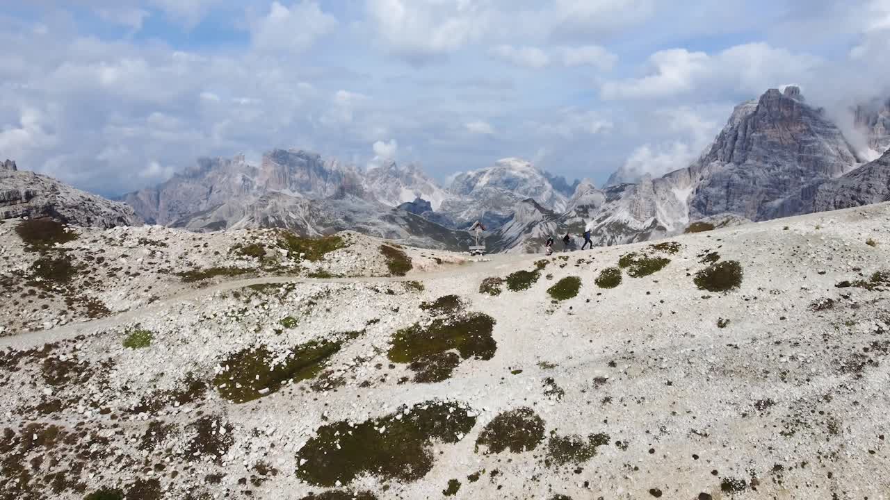 una toma de drones de 3 excursionistas que caminan por un sendero de montaña con una vista excepcional del increíble paisaje de los dolomitas en italia en un día soleado