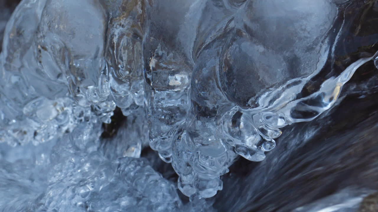 Detail shot of river water flowing during winter with crystal icicles on the side