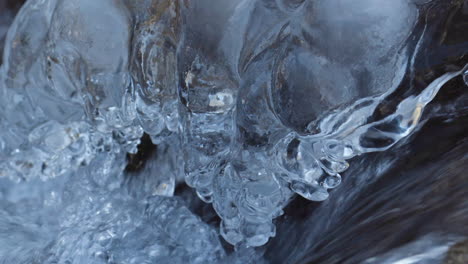 detail shot of river water flowing during winter with crystal icicles on the side