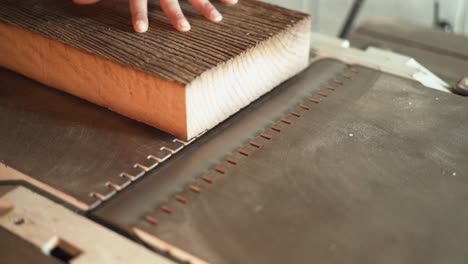 slow motion hand pushing wood along a tabletop planer