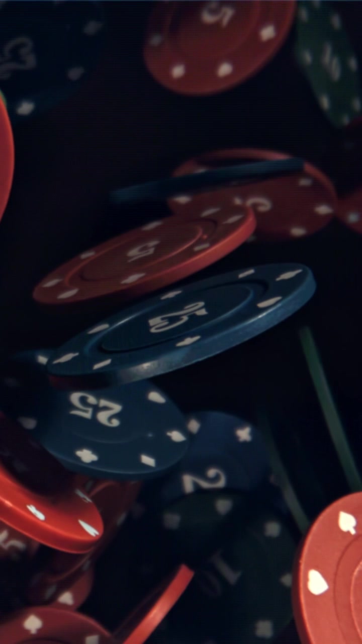 Farverige pokerchips, der falder langsomt mod en mørk baggrund