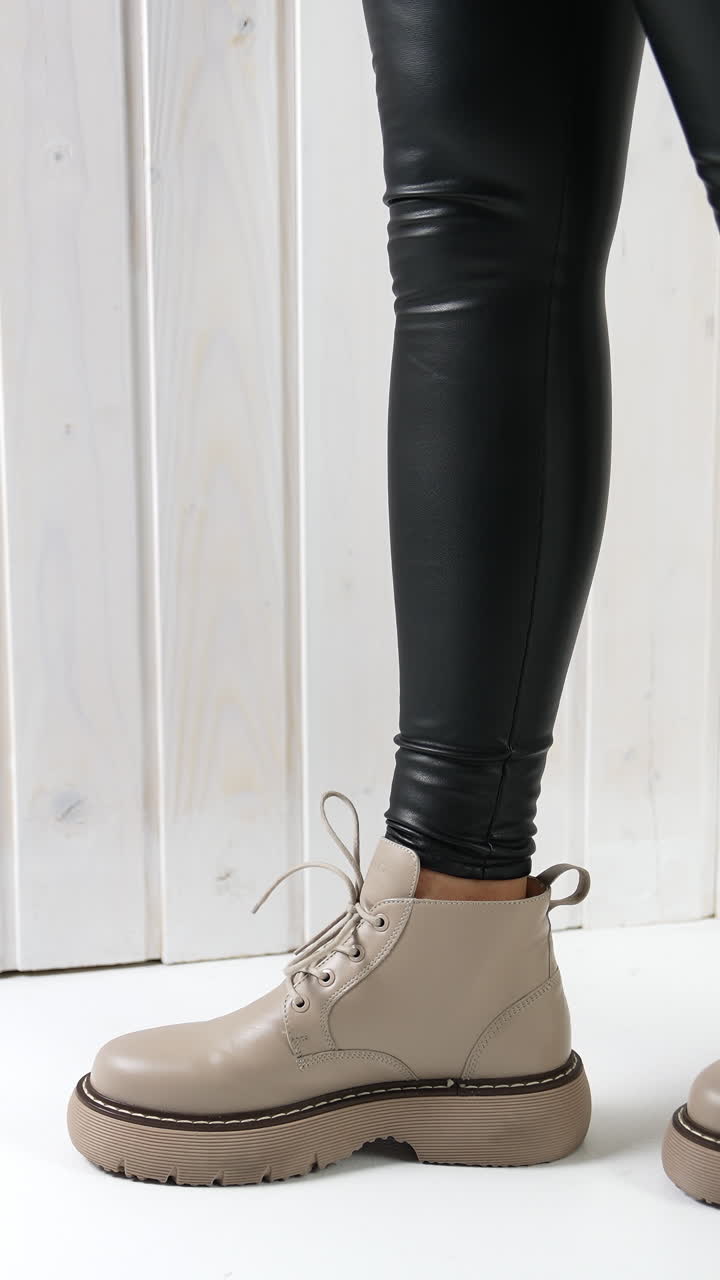 Comfortable leather beige boots on a girl in black leggings. Lady dances to show the beautiful and modern footwear. Vertical video