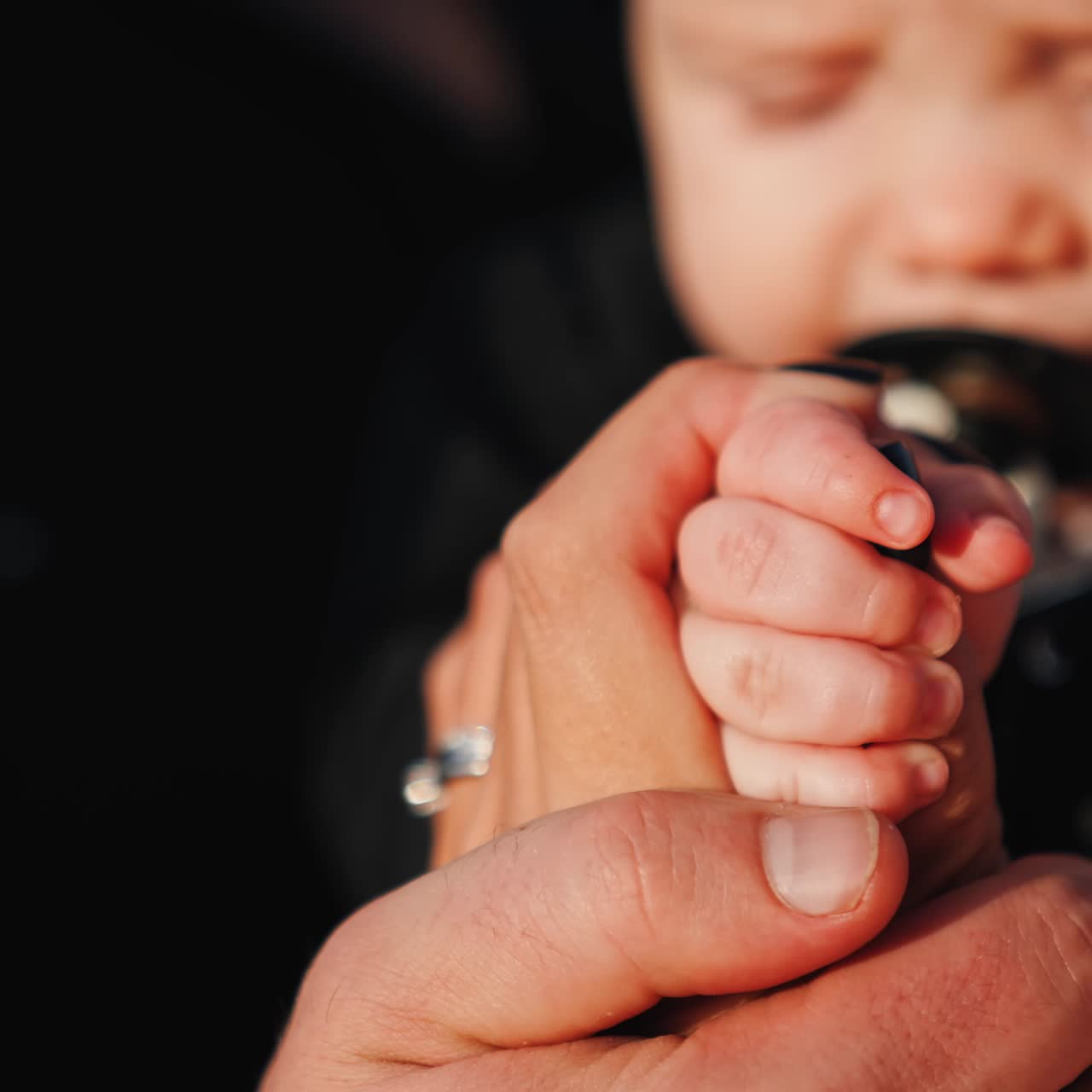 Uomo che accarezza la mano di una donna che tiene la mano di un bambino. Primo piano di una famiglia di tre persone