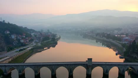 Person,-Die-über-Die-Brücke-In-Visegrad-Geht,-Sonnenuntergangsnebel-Aus-Der-Luft-Von-Oben-Nach-Unten