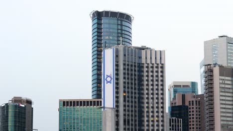 flag of israel on modern skyscraper in downtown tel aviv