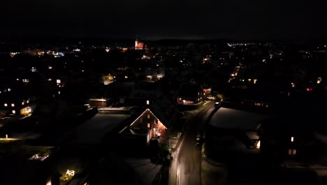 snowy american neighborhood at night. orange lighting streetlamps on dark winter night. housing area with one family houses in usa. aerial top down flyover. wide shot. festive christmas time.