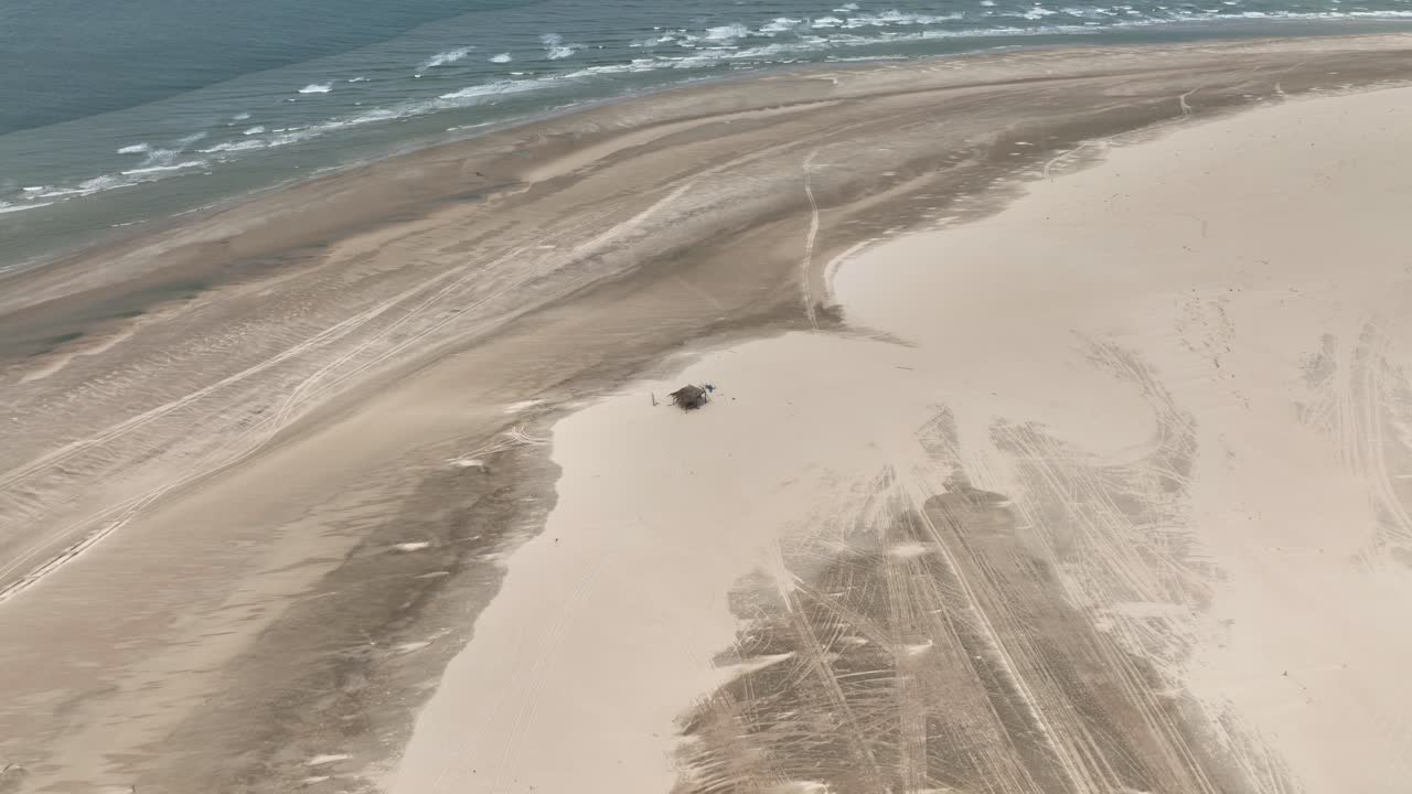 Aerial: small hut on the beach next to Parnaiba River during the day in Araioses, the easternmost city in the Brazilian state of Maranhao, Brazil, establishing drone shot