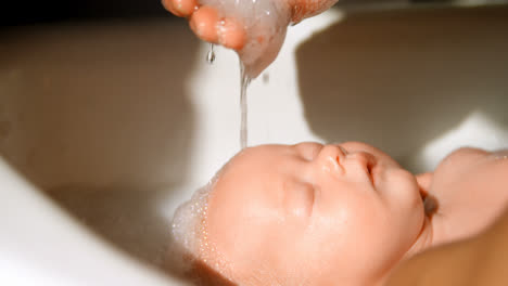 Mother-giving-her-baby-boy-a-bath-in-bathroom-4k