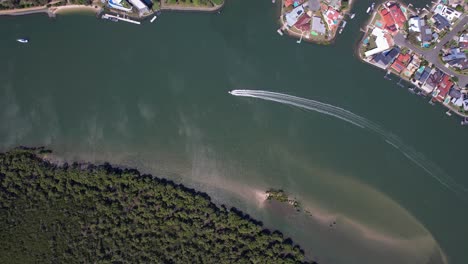 boat cruising and leaving wake on coomera river in paradise point, gold coast, australia