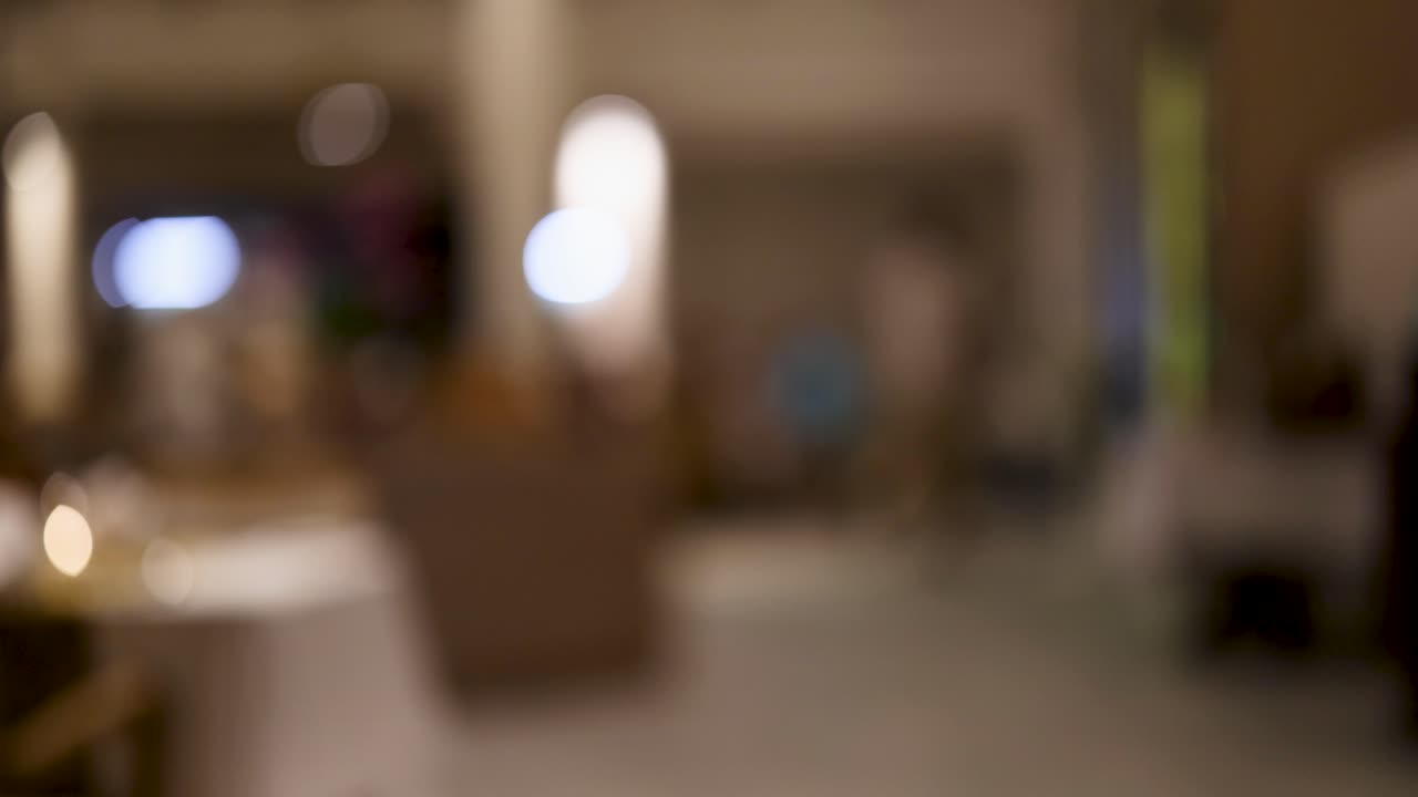 A blurred view of a bustling Thai restaurant at night, capturing ambient lighting and movement in a relaxed setting